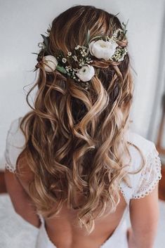 the back of a woman's head with flowers in her hair, sitting on a bed