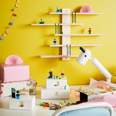 a room with yellow walls and toys on the table, including a white desk lamp