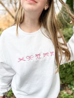 Channel your inner darling with this adorable coquette-inspired sweatshirt, featuring a delicate embroidered bows on the center chest. This soft and cozy crewneck is perfect for layering or wearing on its own, adding a touch of sweetness and femininity to any outfit. Available in a variety of colors to suit your style, this sweatshirt is sure to become a staple in your wardrobe. Features: Soft and comfortable unisex fit Embroidered coquette bow detail Choose your thread color This sweatshirt is perfect for: Casual everyday wear Adding a touch of whimsy to your outfit Gifting to a friend or loved one Shop now and embrace your inner coquette! White Sweatshirt With Embroidered Graphics For Loungewear, White Embroidered Graphics Sweatshirt For Loungewear, White Embroidered Sweatshirt For Loungewear, Cute Cotton Sweatshirt With Custom Embroidery, Cute Cotton Sweatshirt With Embroidered Logo, Embroidered Oversized Tops For Loungewear, Oversized Embroidered Tops For Loungewear, Cute Crew Neck Embroidered Sweatshirt, White Sweatshirt With Letter Embroidery For Loungewear