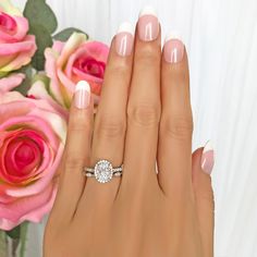 a woman's hand with a diamond ring on it and flowers in the background