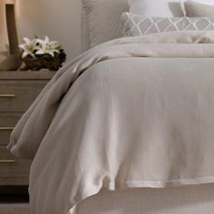 a bed with white linens and pillows in a bedroom