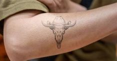 a person with a bull skull tattoo on their arm