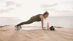 a woman is doing push ups on the beach