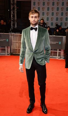 a man in a tuxedo standing on a red carpet