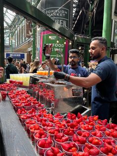 people are shopping for strawberries at an outdoor market