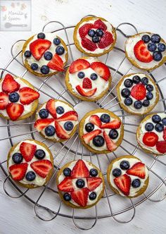 a bunch of desserts that are on a wire rack with strawberries and blueberries