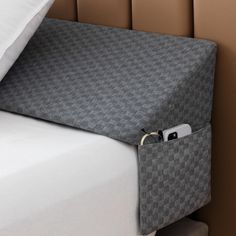 a close up of a bed with a cell phone in the pocket on top of it