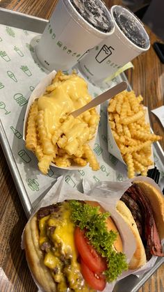 a tray that has some food on it and fries in front of it, along with two drinks