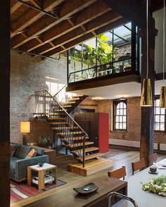 a living room filled with furniture and a spiral staircase in front of a brick wall