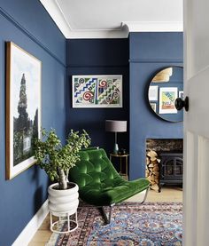 a living room with blue walls and a green chair in front of a mirror on the wall