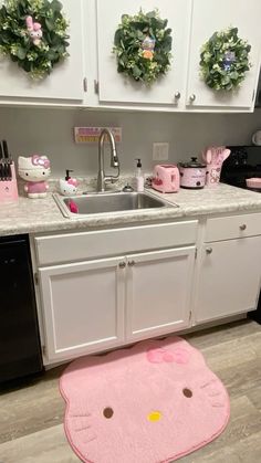 a kitchen with hello kitty rugs on the floor and white cabinets in front of it