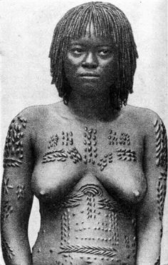 an old photo of a woman with tattoos on her chest and arms, standing in front of