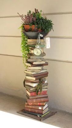 a tall stack of books with plants on top