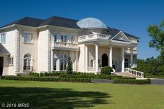 a large white house sitting on top of a lush green field