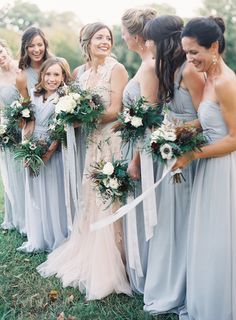 a group of women standing next to each other holding bouquets in front of them