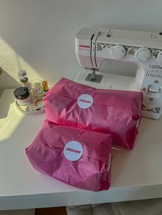 two pink bags sitting on top of a sewing machine