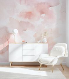 a white chair sitting in front of a wall with pink watercolor paint on it