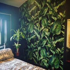 a bed sitting in front of a painting on the wall next to a window with a potted plant