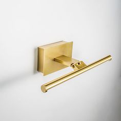 a brass toilet paper holder with a gold towel bar on the wall next to it