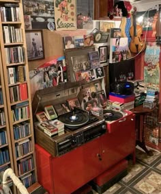 a record player sitting on top of a red cabinet in a room filled with books