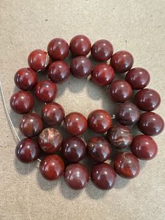 a bunch of red beads sitting on top of a table next to a cord with an object in the middle