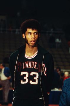 a basketball player standing on the court with his hands in his pockets and looking at the camera