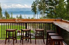 three wooden stools sitting on top of a wooden deck next to a table and chairs