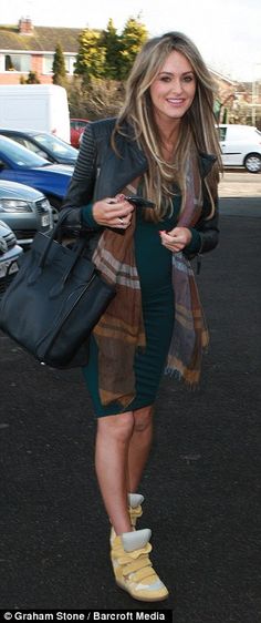 a woman is walking down the street carrying a bag and smiling at the camera with her hand on her hip