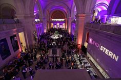 a large group of people standing in a building with purple lighting on the walls and ceiling