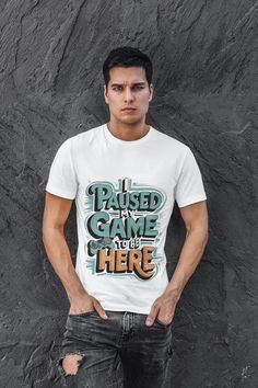 A fun and casual T-Shirt featuring the text "I paused my game to be here" with a gaming controller design.  Perfect for gamers who want to show off their love for gaming in a light-hearted way.  Ideal for everyday wear, lounging around the house, or attending gaming events and conventions.  Great gift for gamers for birthdays, holidays, or as a thoughtful gesture. Product features: - 100% Airlume combed and ring-spun cotton lightweight fabric - Retail fit for casual and semi-formal settings - Side seams for structural support - Ribbed knit collar with seam for shape retention - DTF inner neck labels for comfort Care instructions: - Machine wash: cold (max 30C or 90F) - Non-chlorine: bleach as needed - Tumble dry: low heat - Iron, steam or dry: medium heat - Do not dry clean Return Policy: Graphic Print Crew Neck T-shirt For Gaming Events, Gaming Event Crew Neck T-shirt With Letter Print, Gamer Style White Top For Streetwear, Graphic Tee T-shirt For Gaming Events, Gamer Style Cotton T-shirt With Letter Print, Gamer Style Short Sleeve Top With Letter Print, Gamer Graphic Print Short Sleeve Tops, White Cotton Gamer T-shirt, Graphic Print Short Sleeve Tops For Gaming Events