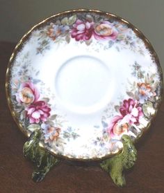 an old china plate with flowers on it sitting on a table top next to a wall