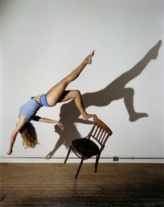 a woman doing a handstand in front of a chair