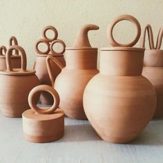 a group of clay pots sitting next to each other on a wooden table with handles