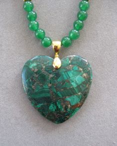 Pretty Small Heart Malachite Pendant Necklace with Malachite beads and gold accents.   It measures 1 1/2 inches by 1 1/2. The necklace is heart shaped and the beads in the necklace are malachite. The necklace is 16 inches and adjustable to 21 inches with Lobster clasp.  The stone is polished. It will go with anything. This is a unique one of a kind necklace.  It comes with a certificate describing the stone. All my jewelry is unique and one of a kind. Similar quality jewelry is priced at double. I source the stone pendants from all over the world. All pendants and necklaces are made with semiprecious stones and beads. I spend hours coordinating the pendants with the semiprecious stone, pearls or crystal beads. Many of the stones are crazy lace agate, dragon vein agate, agate, malachite, ja Green Heart-shaped Beaded Necklace Gift, Green Heart-shaped Beaded Necklace, Green Heart-shaped Beaded Necklaces, Green Heart-shaped Gemstone Necklace, Spiritual Green Jewelry With Heart Beads, Spiritual Green Heart Beads Jewelry, Green Heart-shaped Natural Stone Jewelry, Green Jewelry With Heart Charm And Round Beads, Green Heart Beads Pendant Necklace