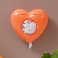 an orange heart shaped object hanging on the wall with ice cubes in it's hole