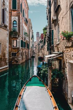 a boat traveling down a canal next to tall buildings and greenery on either side