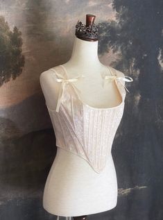 A Historically inspired Tudor, baroque, or renaissance era corset with champagne-ivory colored ornate jacquard fabric is pictured on a mannequin in front of a historic painted landscape backdrop. Stays Corset, Corset Stays, Baroque Era, Fantasy Shop, Tudor Era, Timeless Aesthetic, Medieval Fashion, Rococo Style, Edwardian Fashion