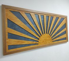 a wooden wall hanging on the side of a white wall with a blue and yellow sun design