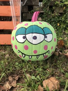 a green and pink pumpkin with an angry face painted on it