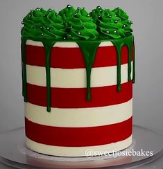 a red and white striped cake with green icing on it's top layer