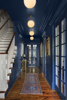 a hallway with blue walls and wooden flooring is shown in this image from the front door