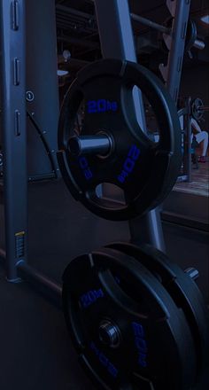 an empty gym room with two black barbells and one blue barbell in the middle