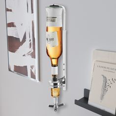 a wall mounted wine glass dispenser next to a shelf with pictures on it