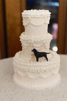 a white wedding cake with a black dog on top