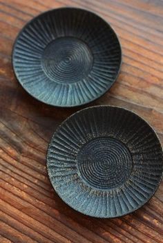 two black plates sitting on top of a wooden table