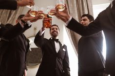 four men in tuxedos toasting with drinks