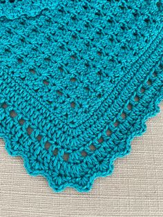 a blue crocheted doily sitting on top of a piece of cloth with holes in it