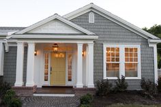 a gray house with white trim and yellow door