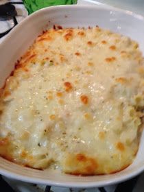 a casserole dish with cheese on top in a white bowl sitting on a stove