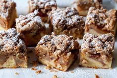 several pieces of dessert sitting on top of a white plate covered in powdered sugar